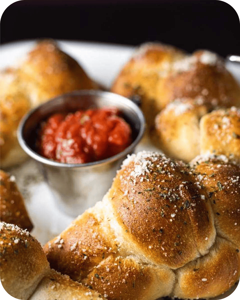 Delicious freshly baked bread rolls with a side of tomato sauce at Albatross Spirits & Dining.