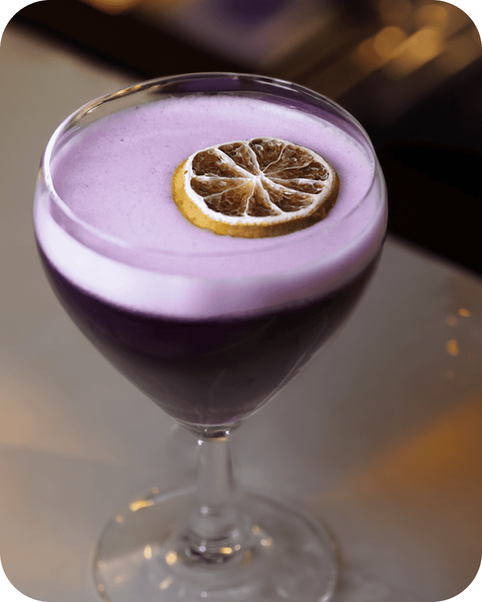 Elegant purple cocktail with lemon slice garnish.